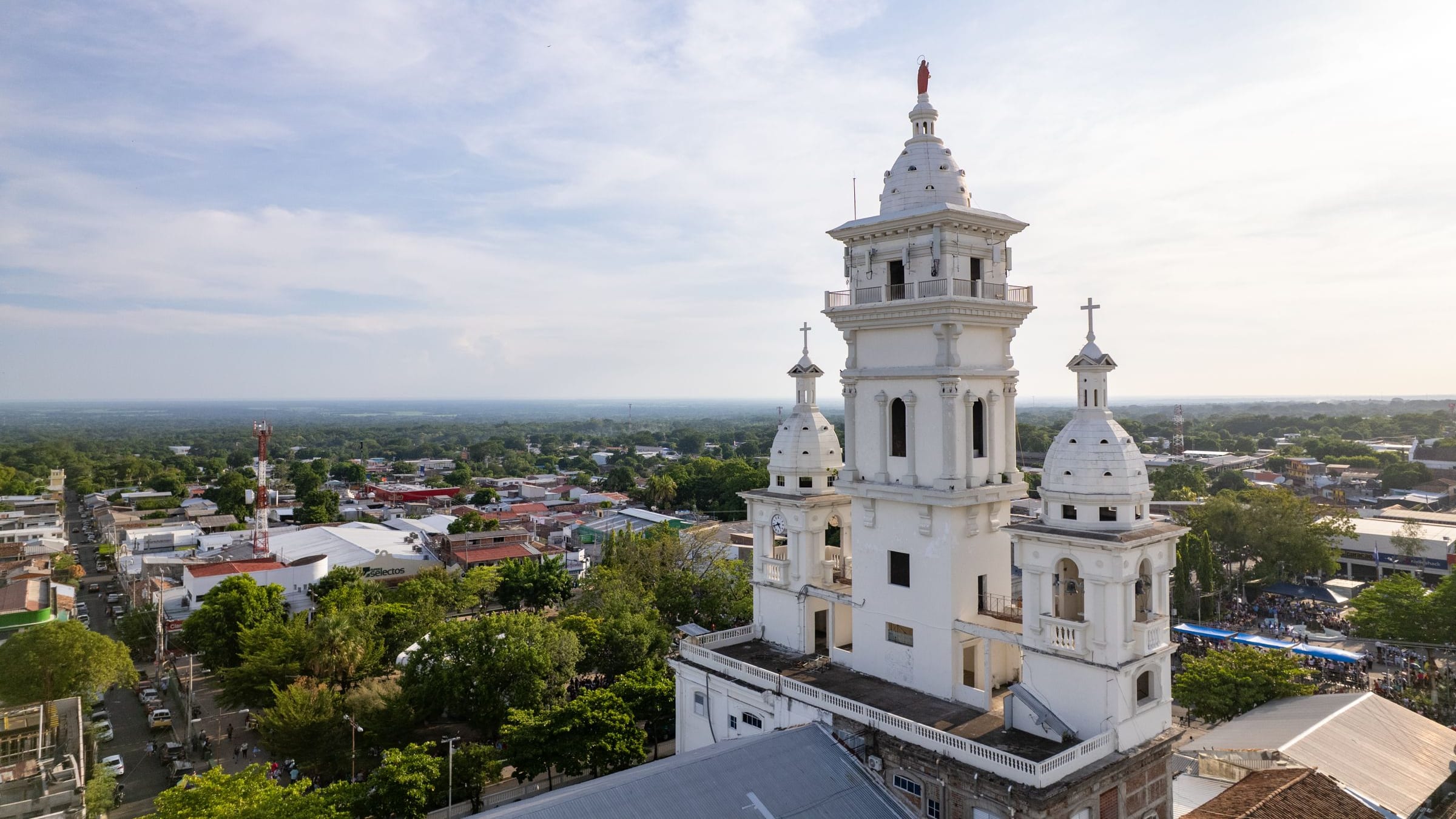 Aerial view of a white church with twin towers and its plaza among the red rooftops of Zacatecoluca, El Salvador